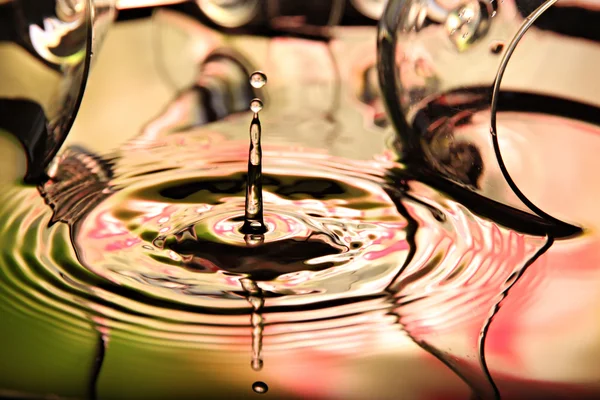 Bilder vatten droppar en vacker form på färgstarka bakgrund. — Stockfoto