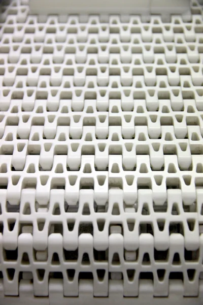 Patterns of white plastic with a conveyor belt.