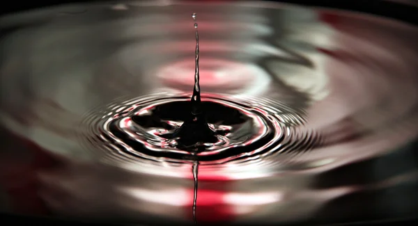 Fondo rojo de agua gotas de una hermosa forma en la cuenca . —  Fotos de Stock