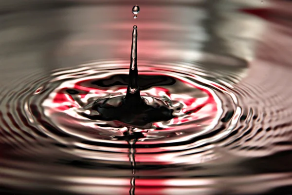 Sfondo rosso di acqua gocce una bella forma in bacino . — Foto Stock