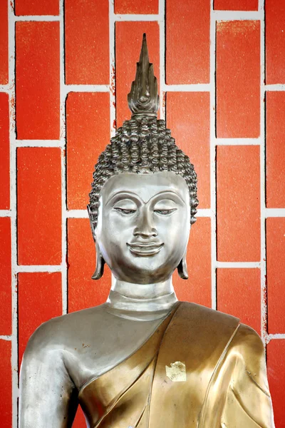 Buddha statue in the background of red Brick. Stock Picture