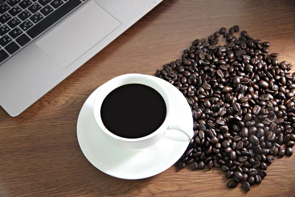 Café en taza blanca y ver las computadoras, granos de café cerca . — Foto de Stock