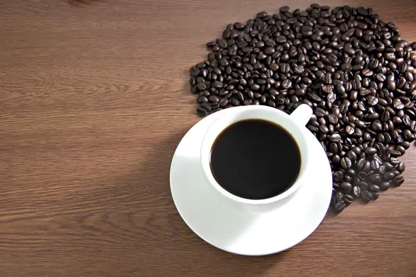 Taza de café y granos de café en la mesa madera vieja . — Foto de Stock