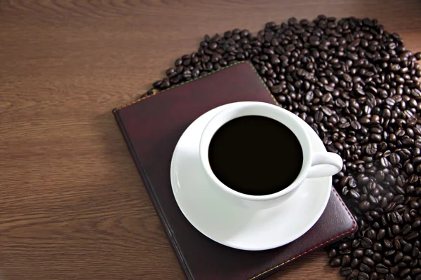 Witte koffiekopje en boek over de tabel oud hout in de buurt van de koffie — Stockfoto