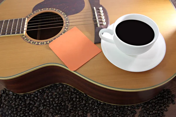 White coffee cup and Notebook paper orange resting on guitar. — Stock Photo, Image