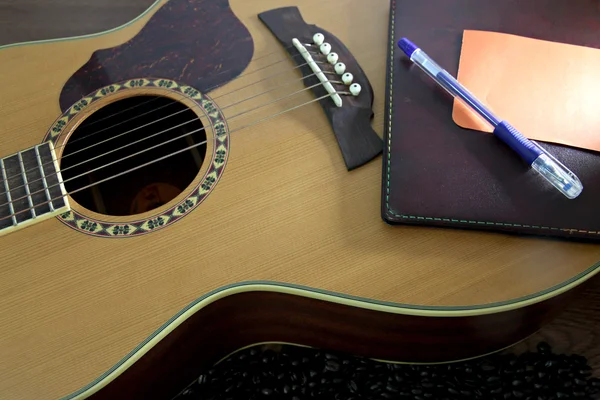 Notebook and Pen resting on the guitar. — Stock Photo, Image