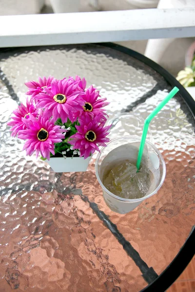 Purple flowers on table near the glass of ice. — Stock Photo, Image