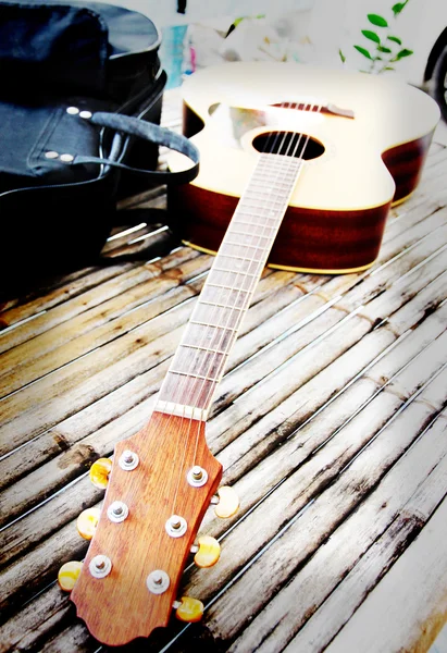 Guitar resting on bamboo desk. — Stock Photo, Image
