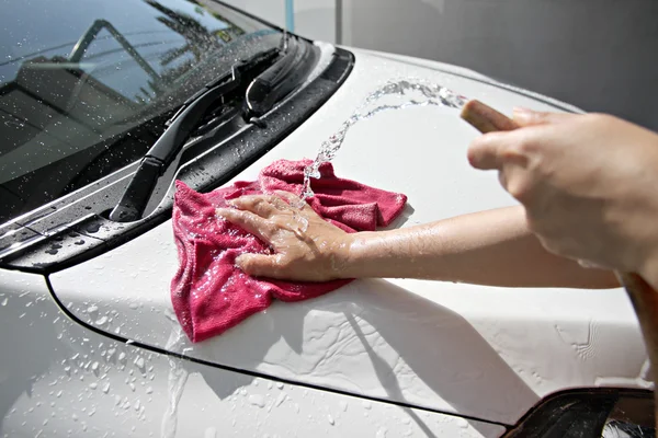 White car washing with fabric and Water hose.