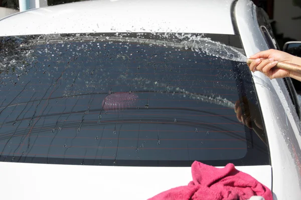Lavagem de carro branco com tecido e mangueira de água em casa . — Fotografia de Stock