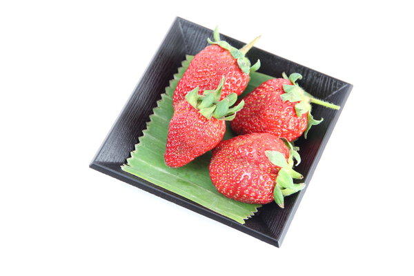 Strawberry in black bamboo dish.