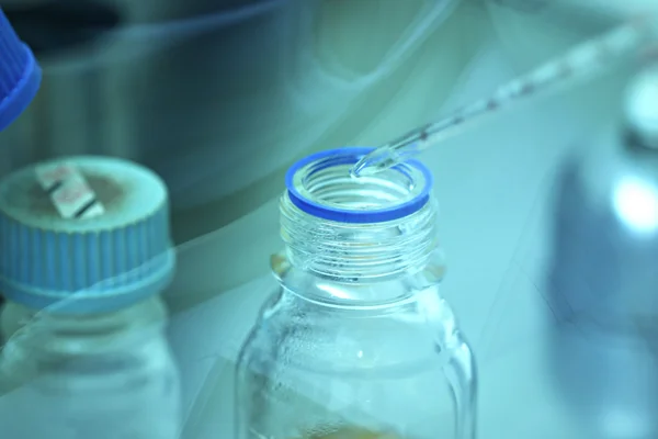 Pipette adding fluid water to test bottle. — Stock Photo, Image