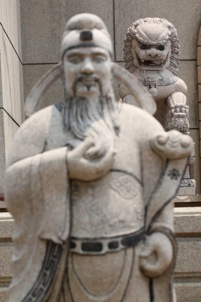 Statues of Chinese deity in focus lion sculpture. — Stock Photo, Image