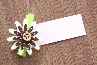 Yapay çiçek ve koyu ahşap üzerine yapışmış not kağıdı.