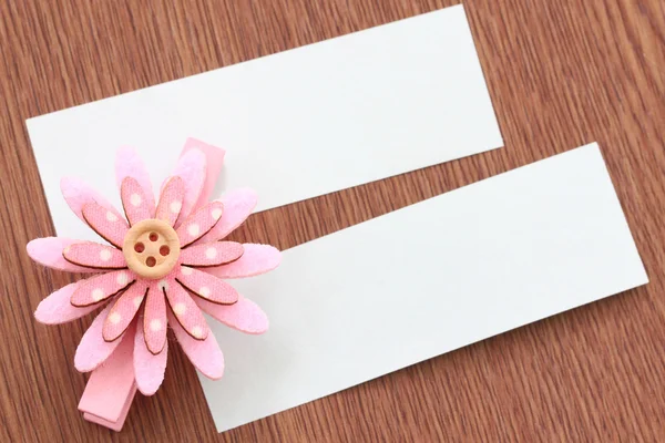 Flores artificiales rosadas y papel de nota pegados en madera oscura . —  Fotos de Stock