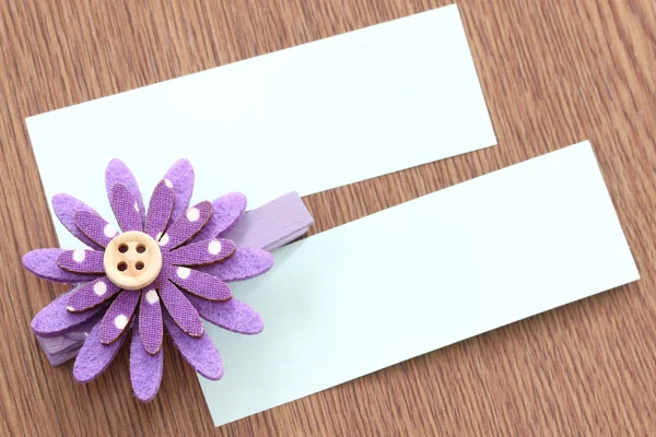 Purple artificial flowers and note paper stuck on dark wood. — Stock Photo, Image