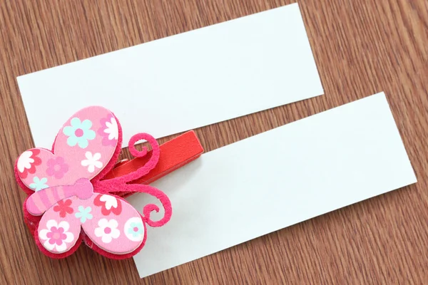 Pink artificial butterfly and note paper stuck on dark wood. — Stock Photo, Image