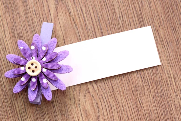 Purple artificial flowers and note paper stuck on dark wood. — Stock Photo, Image