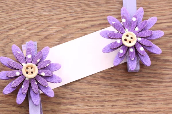 Purple artificial flowers and note paper stuck on dark wood. — Stock Photo, Image