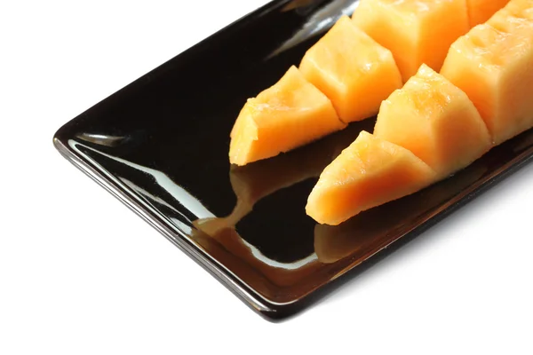 Slices cantaloupe melon fruit in blackdish. — Stock Photo, Image