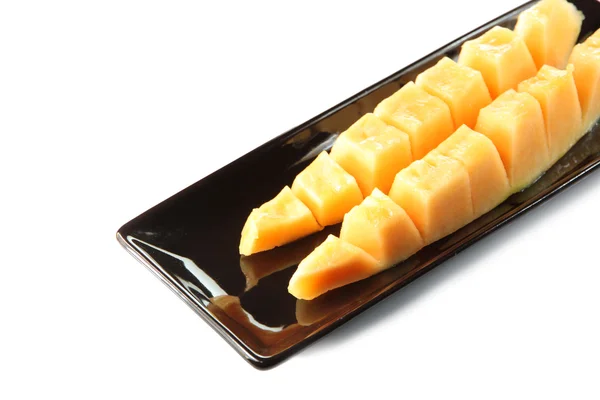 Slices cantaloupe melon fruit in blackdish. — Stock Photo, Image