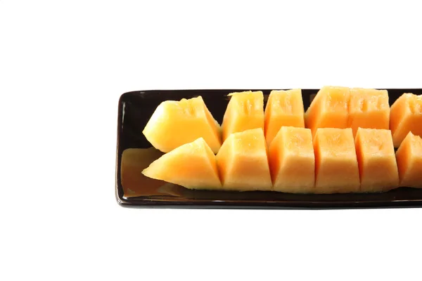 Slices cantaloupe melon fruit in blackdish. — Stock Photo, Image