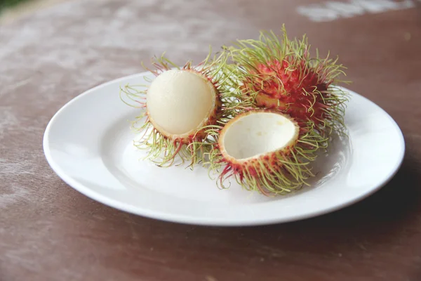 Fruta de rambutão fresca de descascar em prato . — Fotografia de Stock