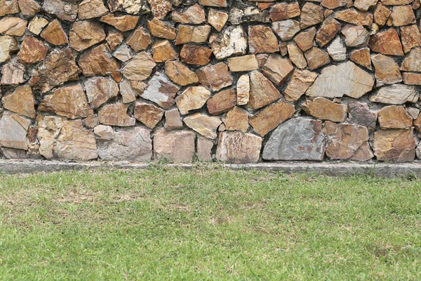 Brown stone wall and green lawn. — Stock Photo, Image