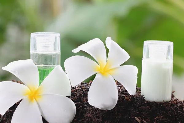 White frangipani and perfume bottle on ground. — Stock Photo, Image