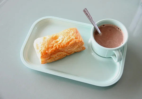 Patty y cacao caliente en un plato azul en la mesa de comedor . —  Fotos de Stock