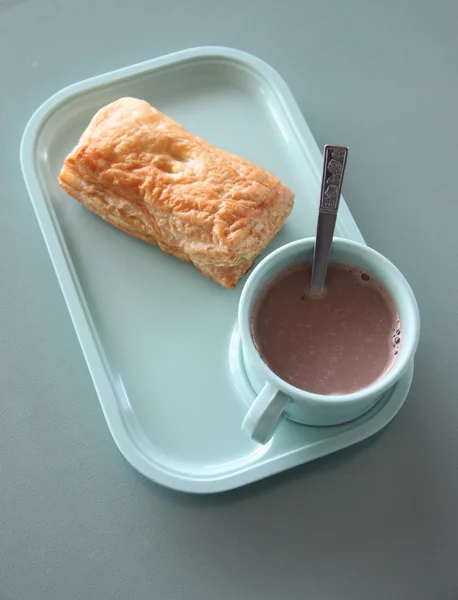 Patty och varm choklad i en blå skål på matbord. — Stockfoto