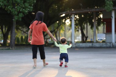 Anne ve çocuk parkta yürümek için el ele tutuşuyorlar, anne ve çocuk arasındaki sevgi kavramı..