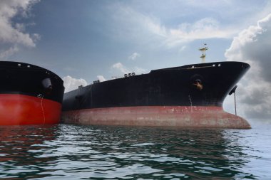 Denizin ortasındaki büyük bir kargo gemisinin başındaki kargo gemileri kargoyu denizin ortasındaki bir gemiye yükleyip taşıyorlar..