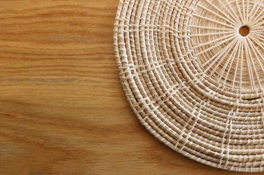 Kahverengi ahşap masada servis yapmak için yuvarlak rattan yapılmış sepet..