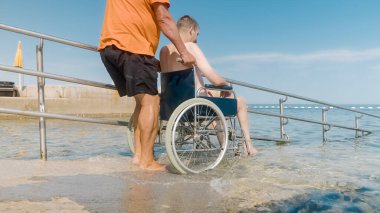 Tekerlekli sandalyedeki adam rampadan denize
