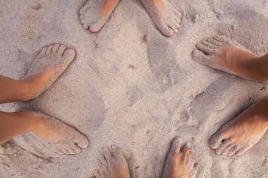 Kumlu sahilde insanların ayakları