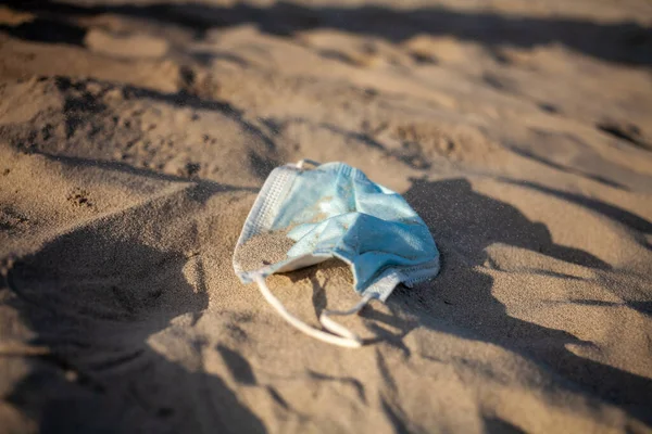 Disposable medical mask on beach by sea — Stock Photo, Image