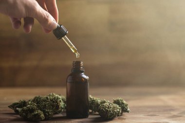 CBD yağlı bir pipetle el ele tutuşmak