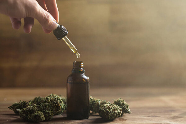Рука держит пипетку с маслом CBD