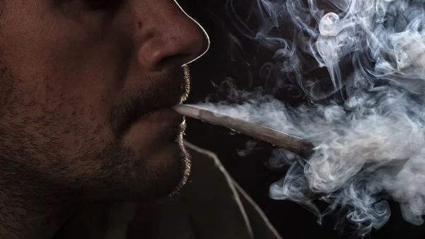 Uomo con una canna di marijuana in bocca — Foto Stock