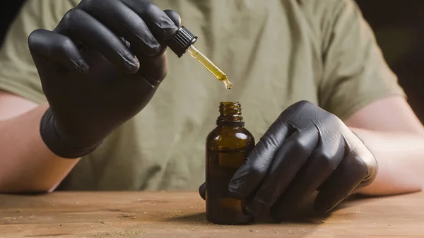Hands dripping CBD oil drops — Stock Photo, Image