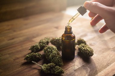 CBD yağlı bir pipetle el ele tutuşmak