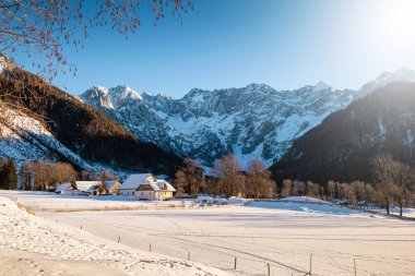 Güneşli bir kış gününde, bir dağ vadisinde karlı bir köy.