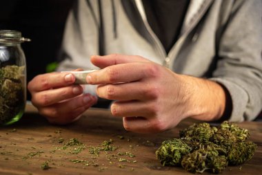 Erkek eller marihuana yapıyor.