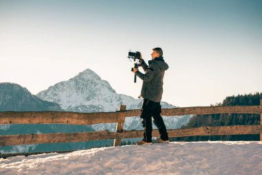 Kameraman karda çekim yapıyor ve arka planda dağlar var..