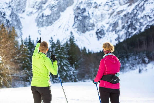 Kaukasisches Paar beim Skifahren am Fuße eines atemberaubenden Berges — Stockfoto