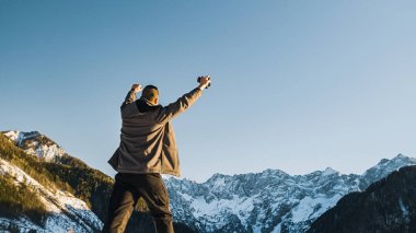 Genç adam dağın zirvesine karların içinden yürüyerek ulaşır.