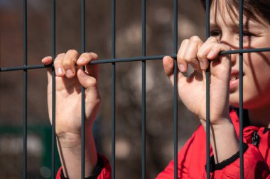 Metal bir çitin arkasında çocuk mülteci var