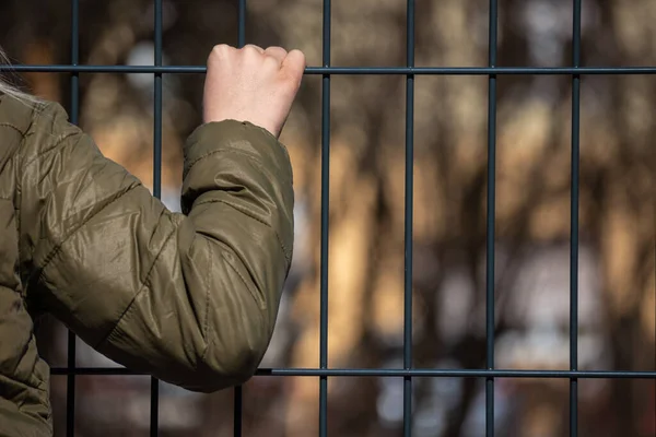 Рука дитини-біженця тримає металевий паркан — стокове фото