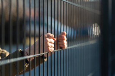 Metal bir çitin arkasında çocuk mülteci var